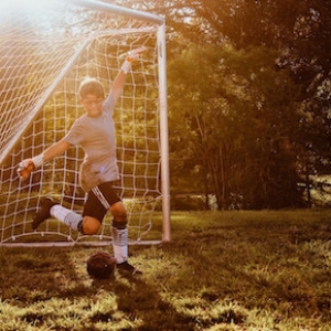 custom soccer uniforms kid kicking ball in goal